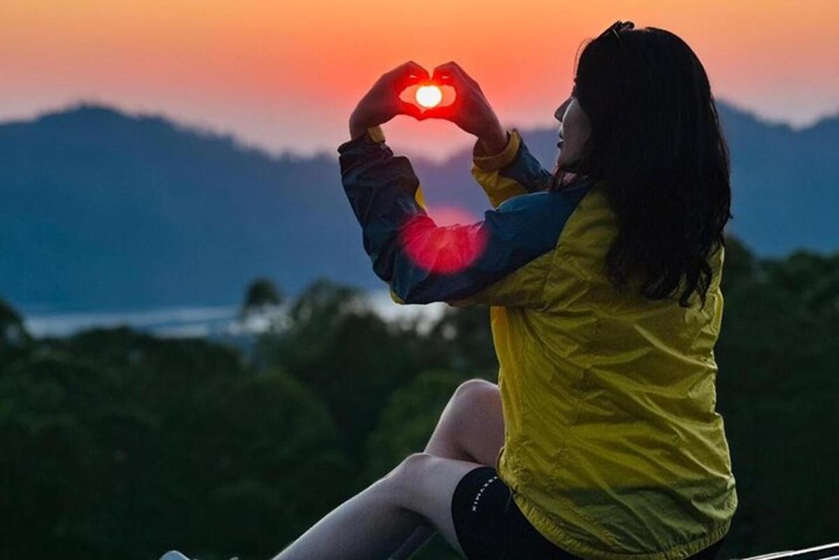 una donna seduta in cima a una collina che tiene in mano un cuore
