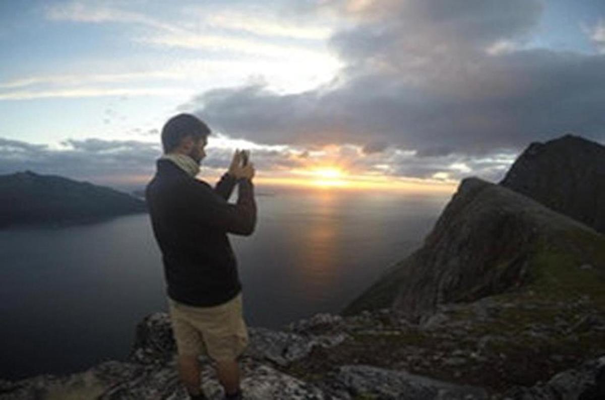 moški fotografira sončni zahod na gori