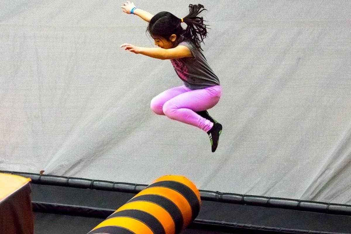 ein kleines Mädchen, das von einem Trampolin springt