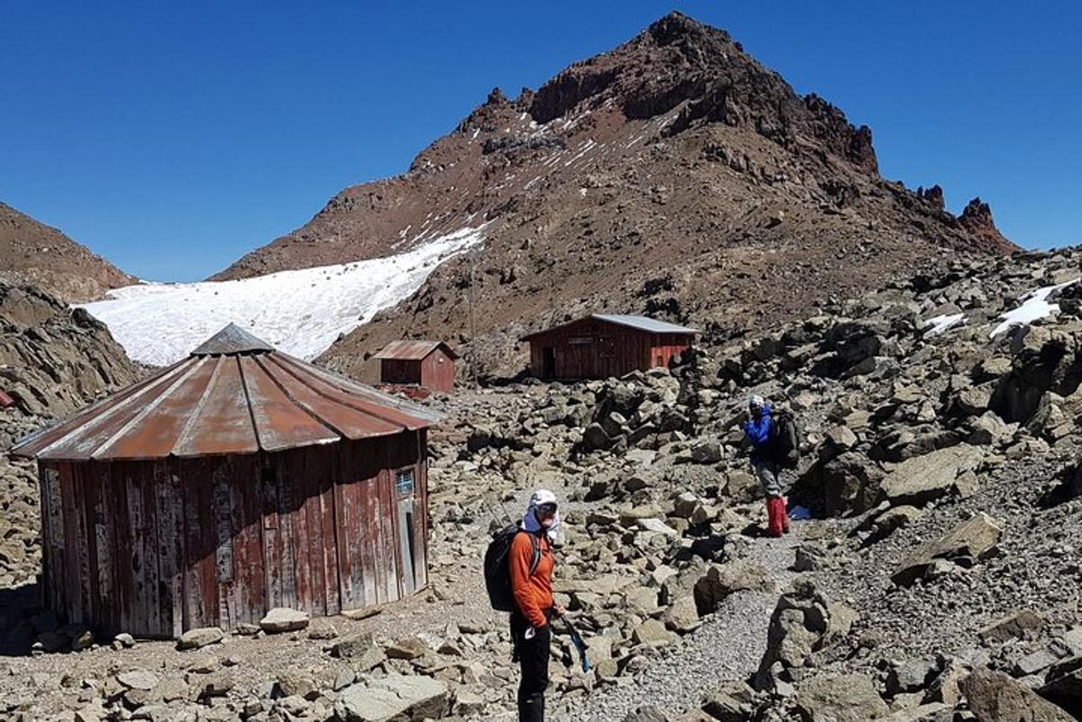 un uomo in piedi accanto a un edificio su una montagna rocciosa