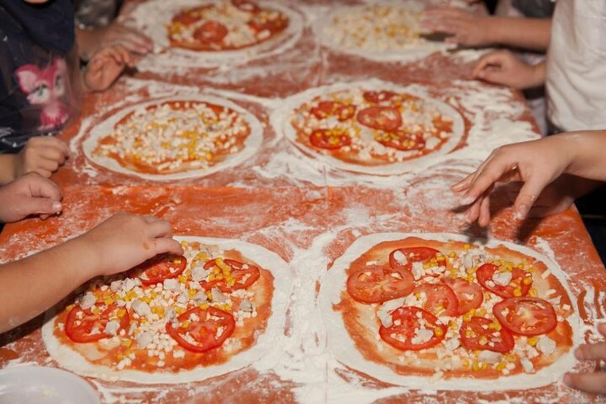 sekumpulan orang membuat pizza di atas meja