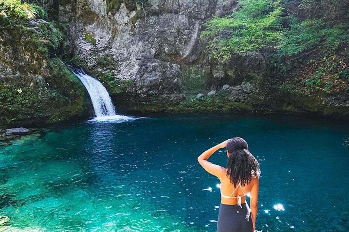 eine Frau, die im Wasser in der Nähe eines Wasserfalls steht