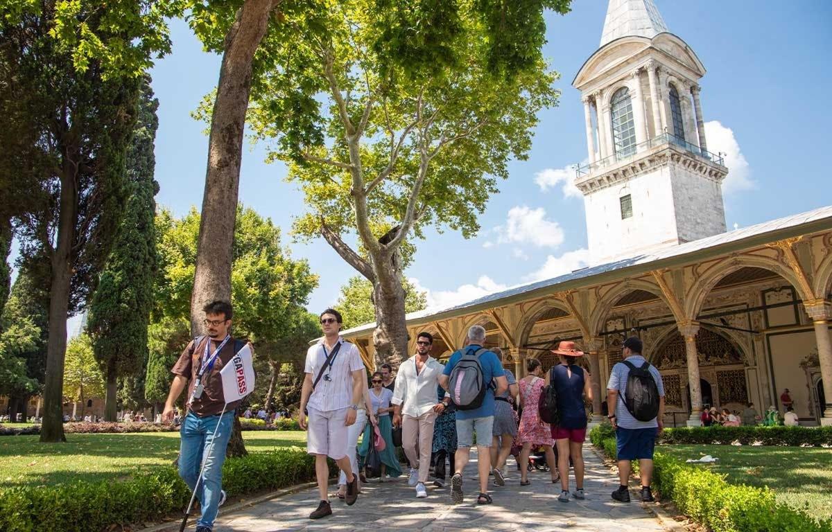 um grupo de pessoas caminhando em frente a um prédio com uma torre