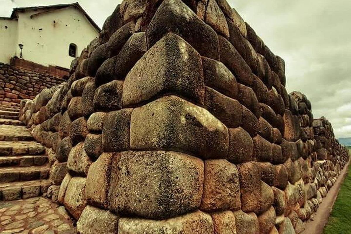 un muro di contenimento in pietra con un edificio sullo sfondo