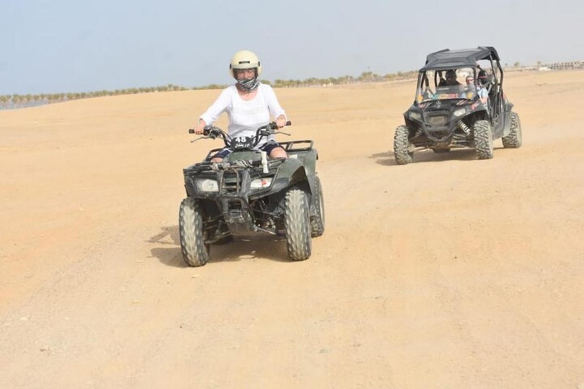 hai người trên xe địa hình và một chiếc xe jeep trong sa mạc