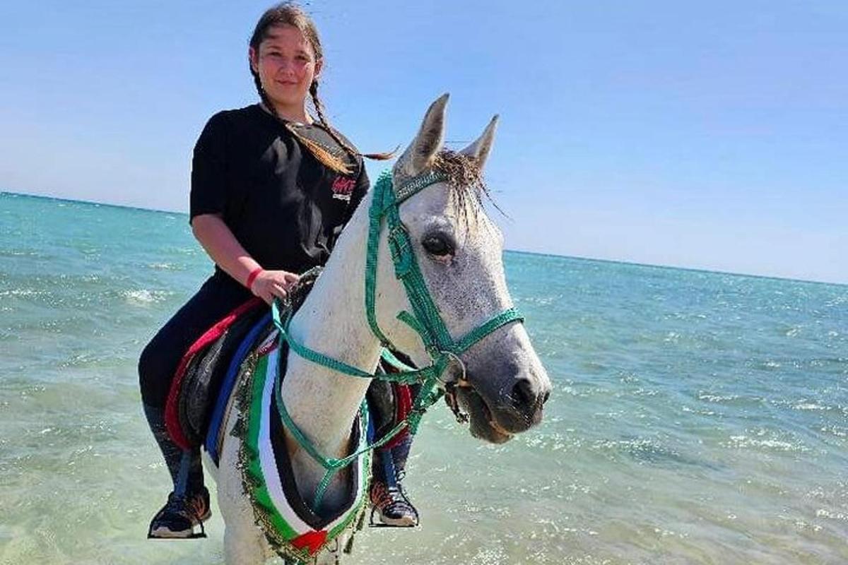 una dona muntant a cavall a la platja