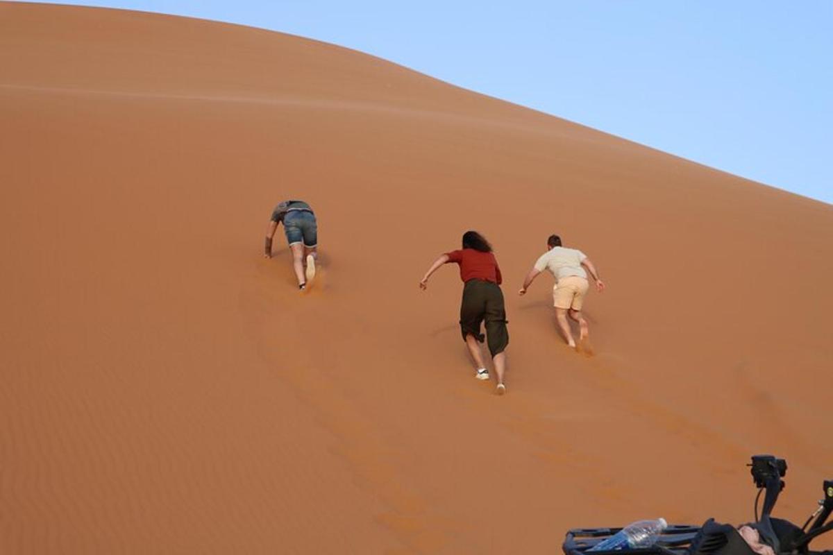 traja ľudia kráčajúci po piesočnej dune