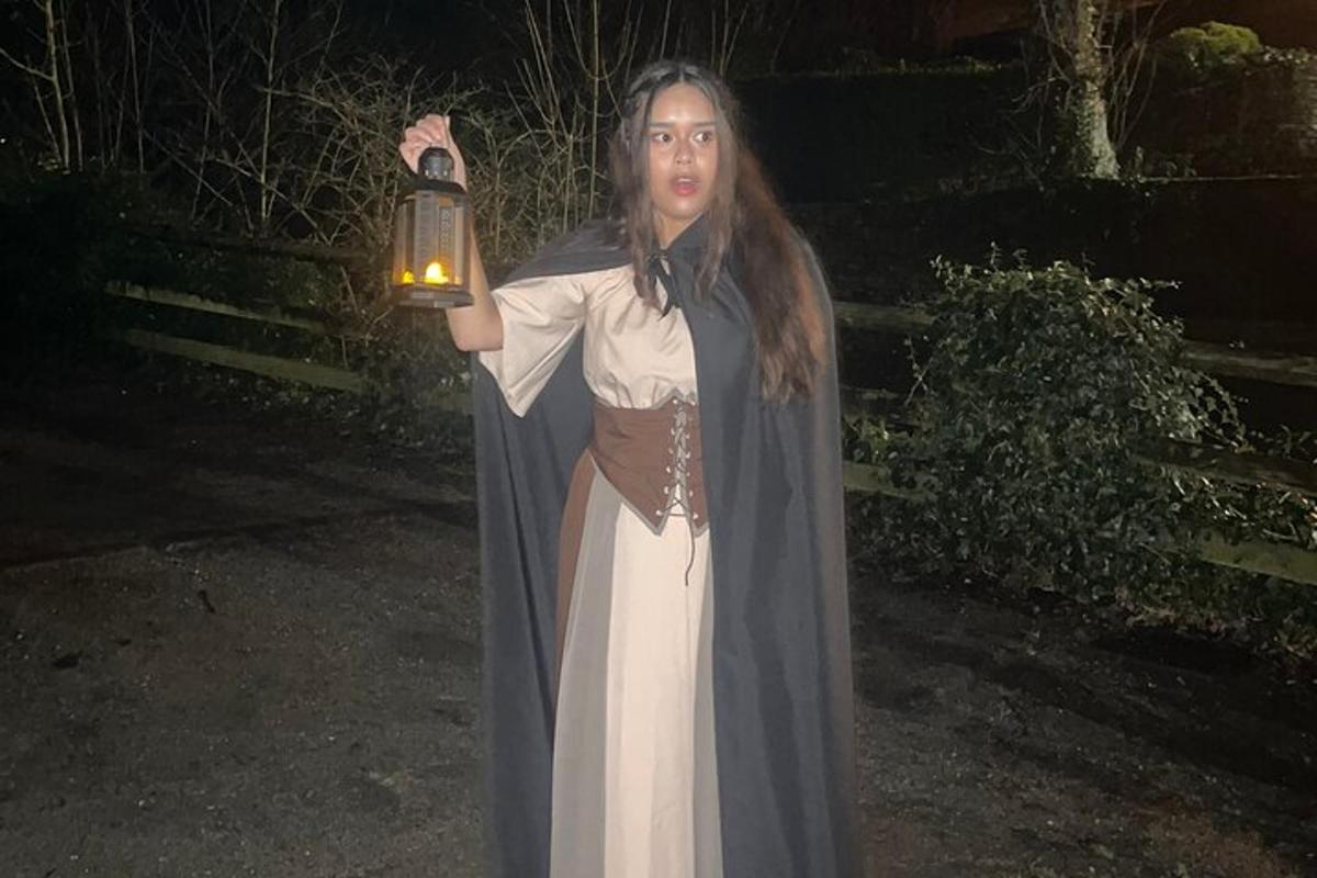 a girl in a dress holding a lantern at night