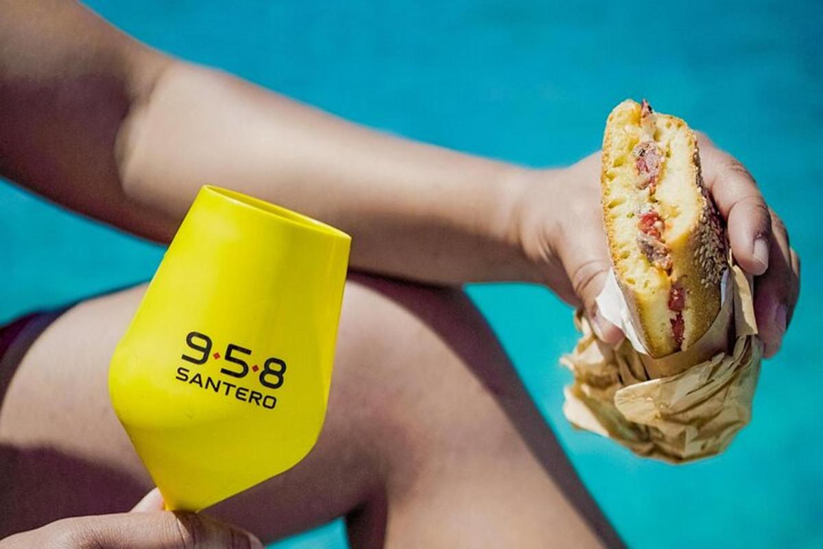 eine Person, die einen Hotdog und einen gelben Becher hält