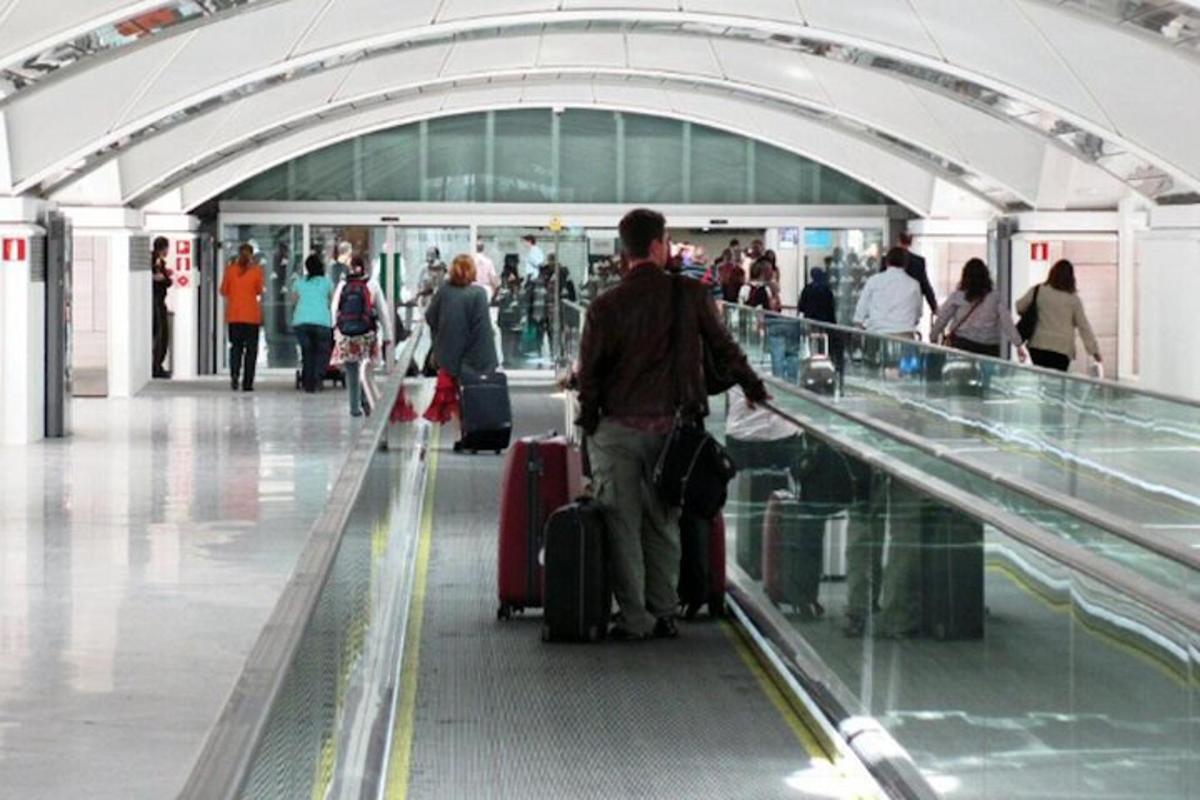 un uomo che scende da una scala mobile con i bagagli in un aeroporto