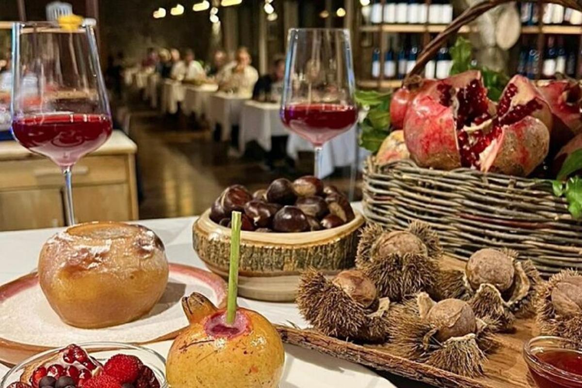 Una mesa con dos copas de vino y cestas de fruta.