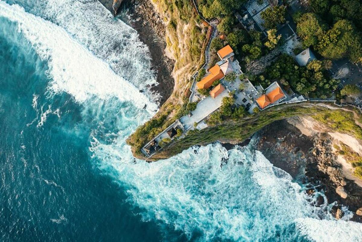 an aerial view of a house on a cliff next to the ocean