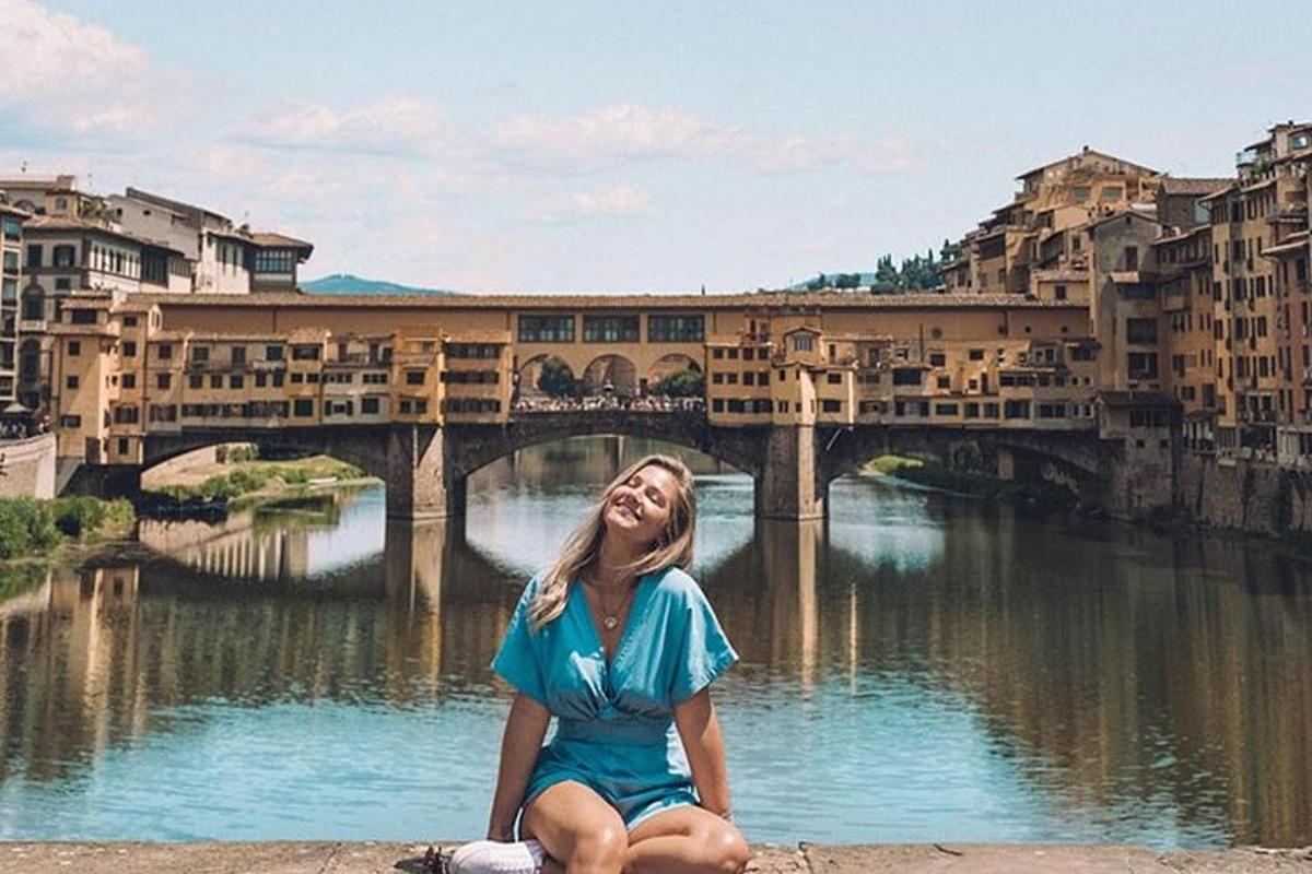 žena sedící vedle řeky před mostem