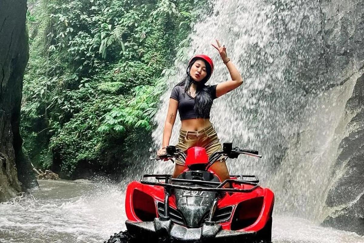 una donna in piedi su una motocicletta davanti a una cascata