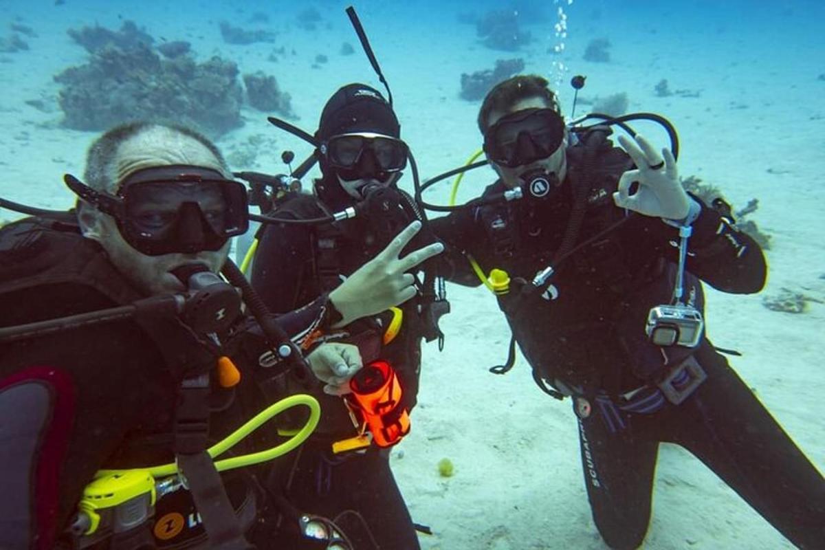 um grupo de três pessoas com equipamento de mergulho no oceano