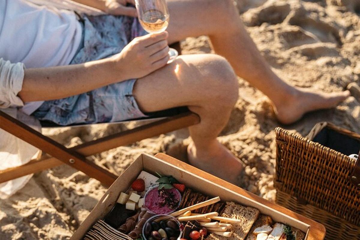 eine Frau, die mit einem Glas Wein am Strand sitzt