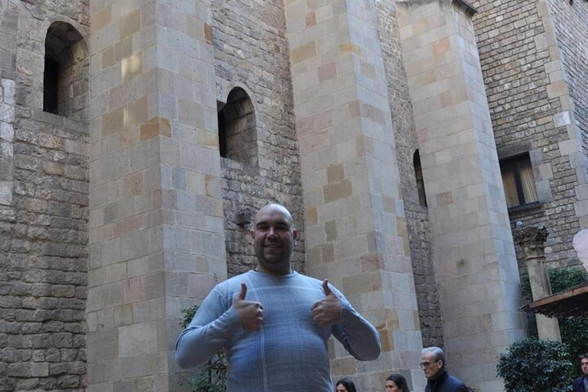 un home fent el signe d'aprovació davant d'un edifici