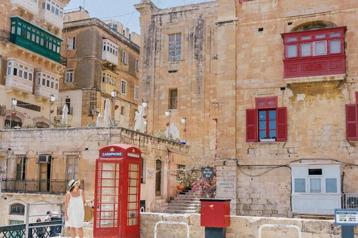 a woman standing next to a red phone booth in front of a building