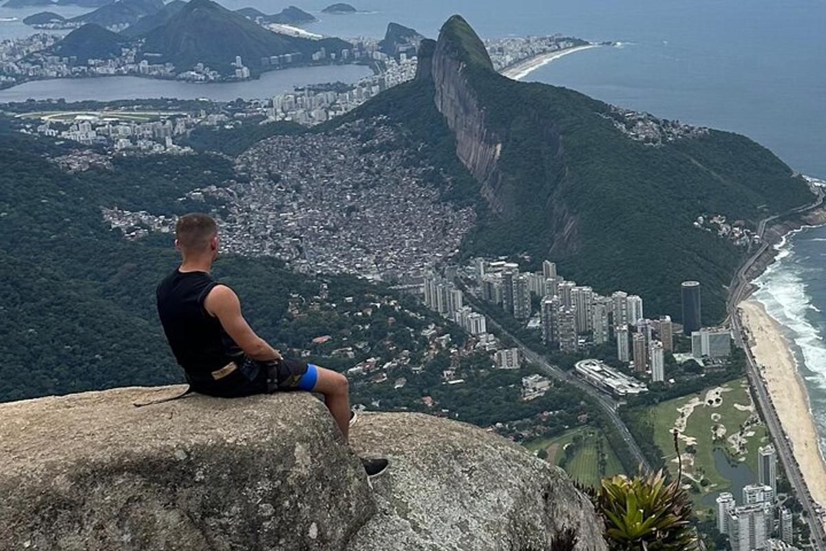 un uomo seduto in cima a una roccia che domina la città