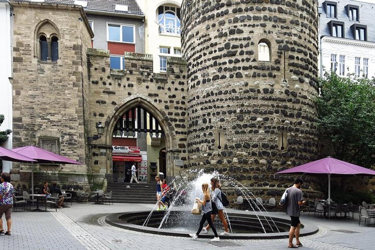 a group of people walking around a fountain in front of a building