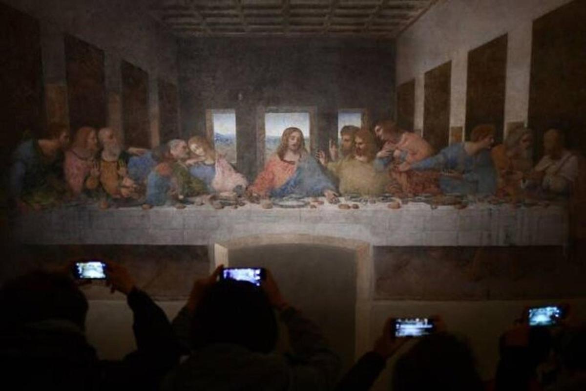 um grupo de pessoas tirando fotos de uma pintura na parede