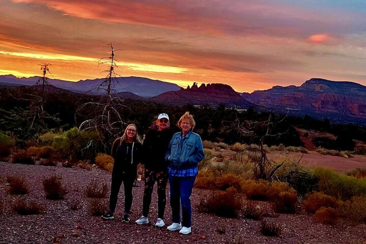 Tres personas de pie en el desierto al atardecer