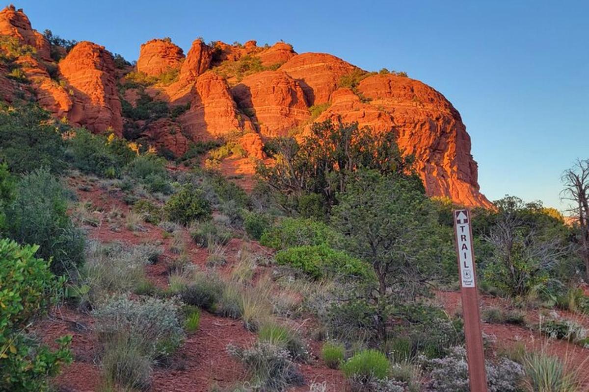 Un cartel delante de una montaña con rocas rojas.