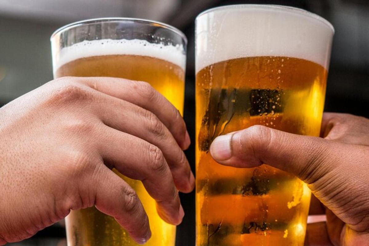 two people are holding glasses of beer
