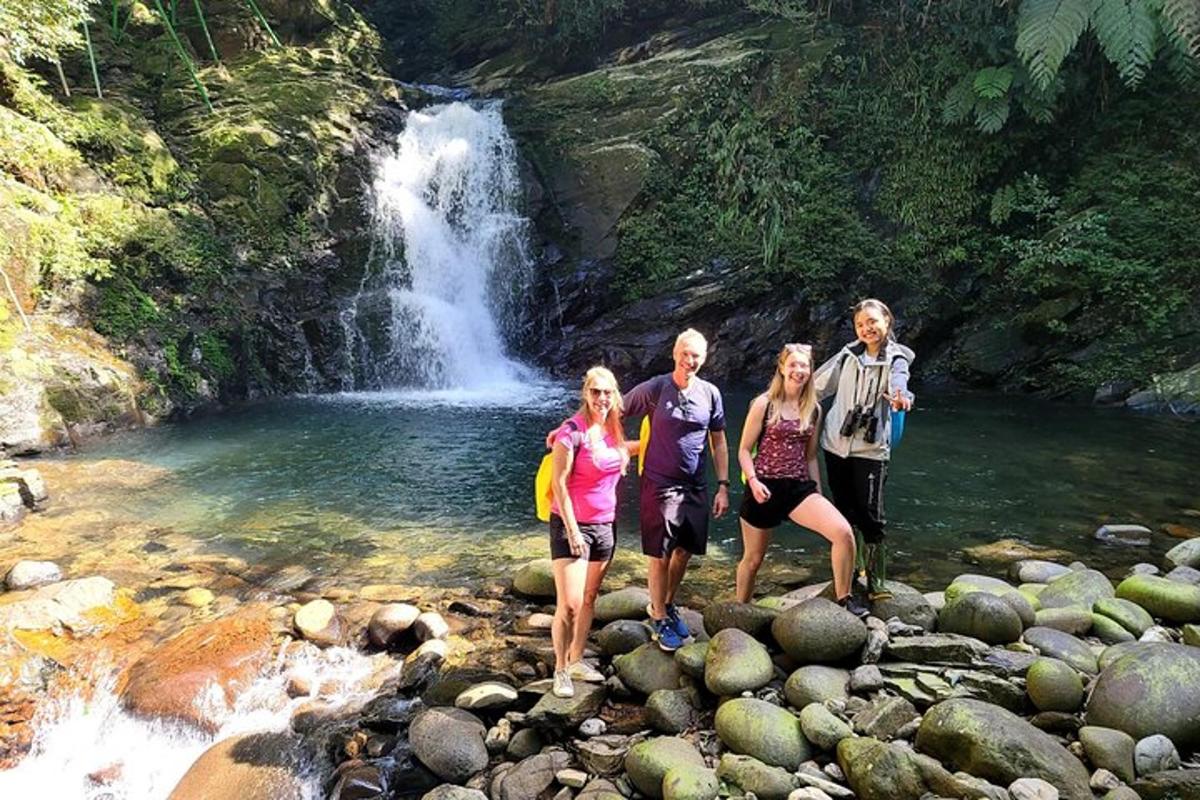 Un grupo de personas de pie sobre rocas frente a una cascada.