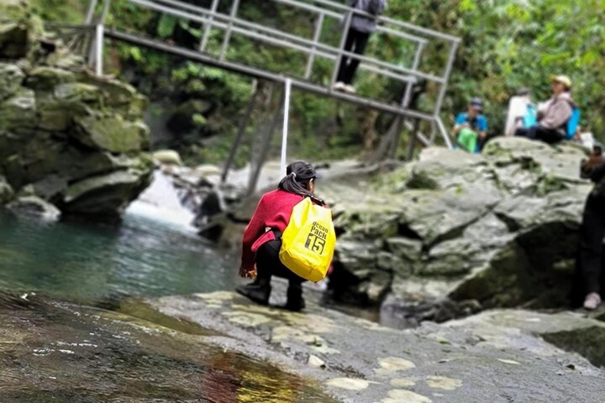 Una persona está parada en un río con una bolsa amarilla.