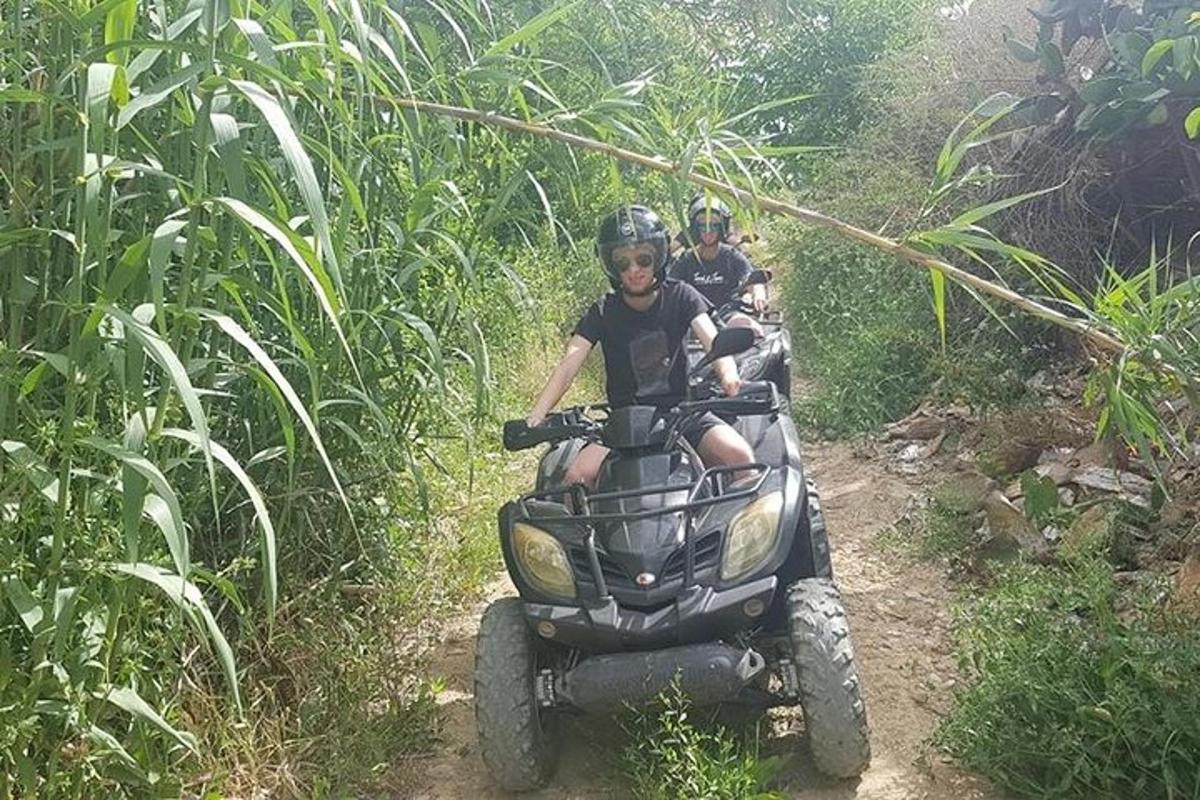 dva lidé jedoucí na čtyřkolce na stezce
