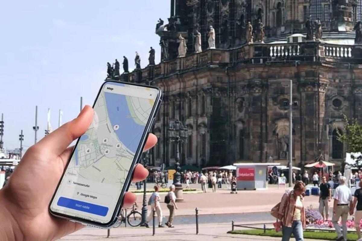 osoba držící mobilní telefon před budovou