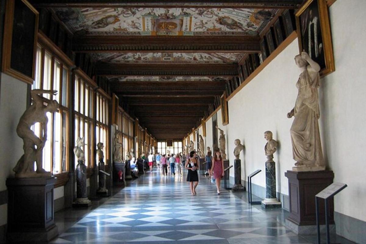 persone che camminano lungo un corridoio in un museo con statue