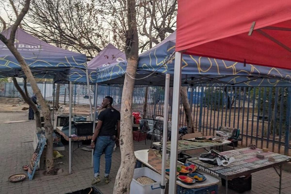Un hombre parado frente a un mercado con paraguas.