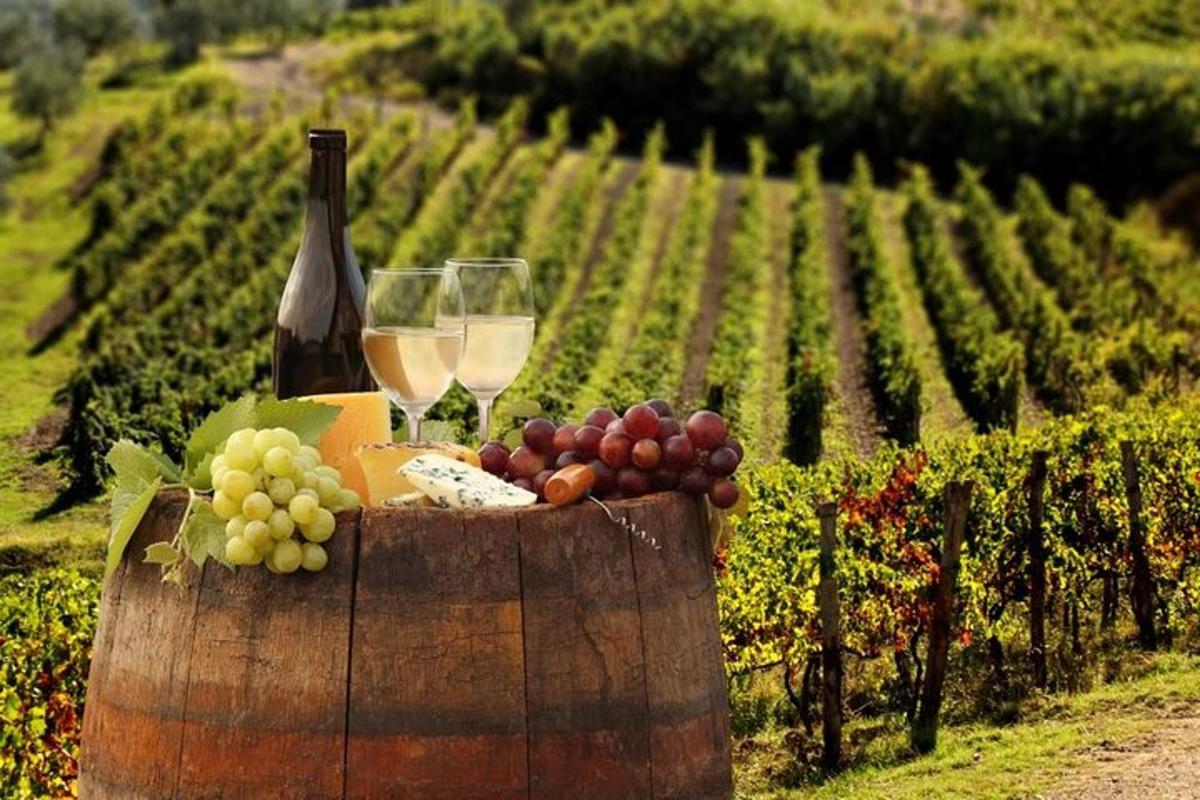 a barrel with wine glasses and grapes on a vineyard