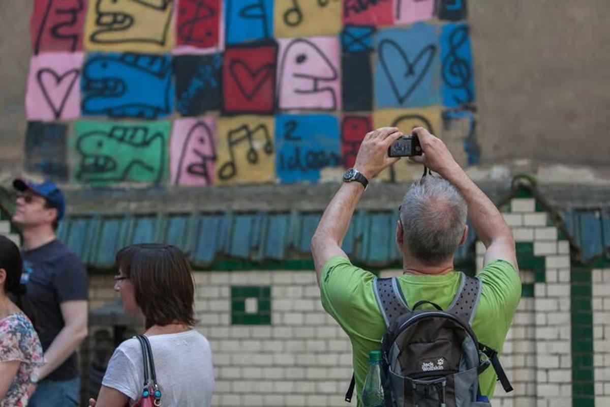 um homem tirando uma foto de uma parede de grafite