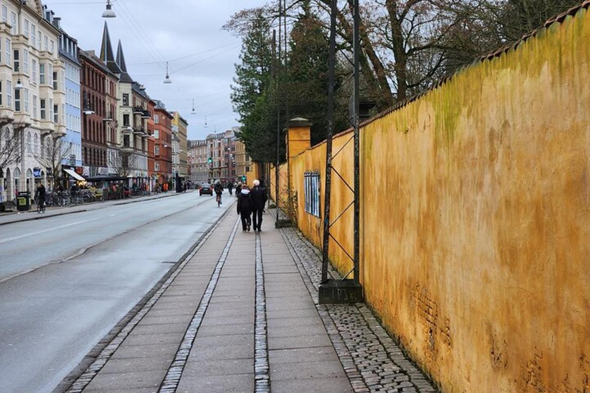 két ember sétál az utcán egy fal mellett