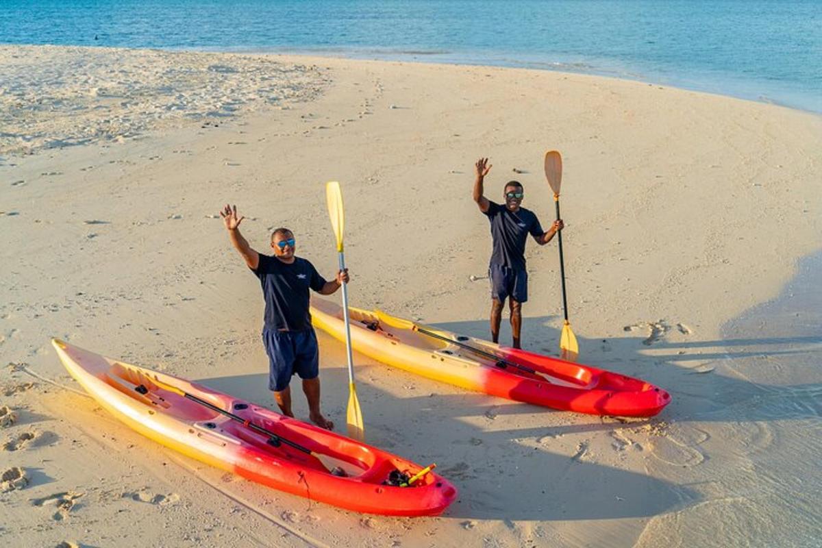two men are standing on the beach with their kayaks