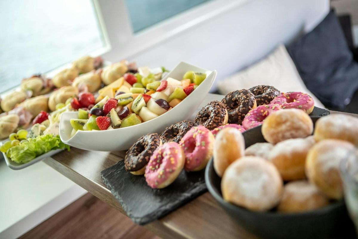 pöytä, jonka päällä on donitsilautasia ja hedelmäkulhoja