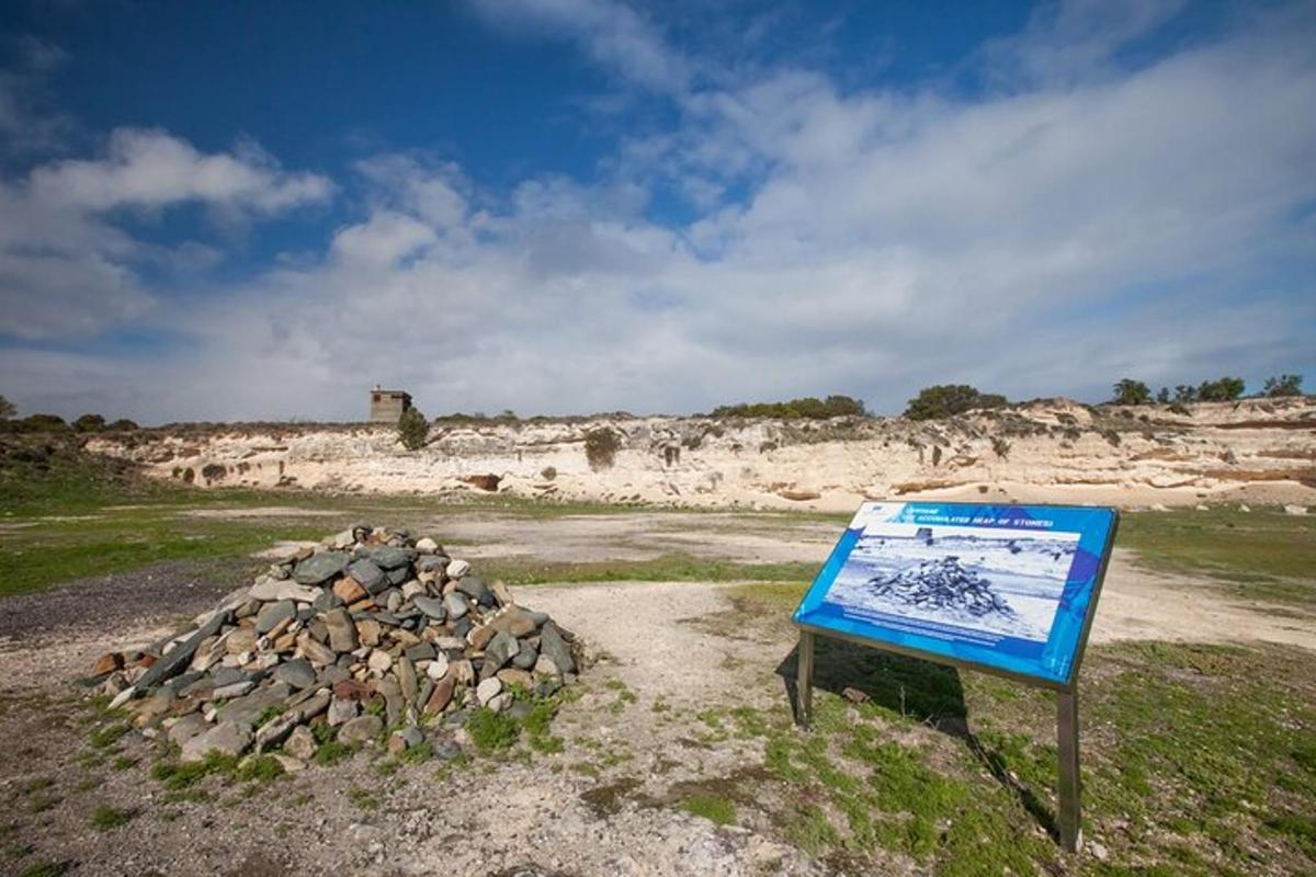 a sign in a field with a pile of rocks