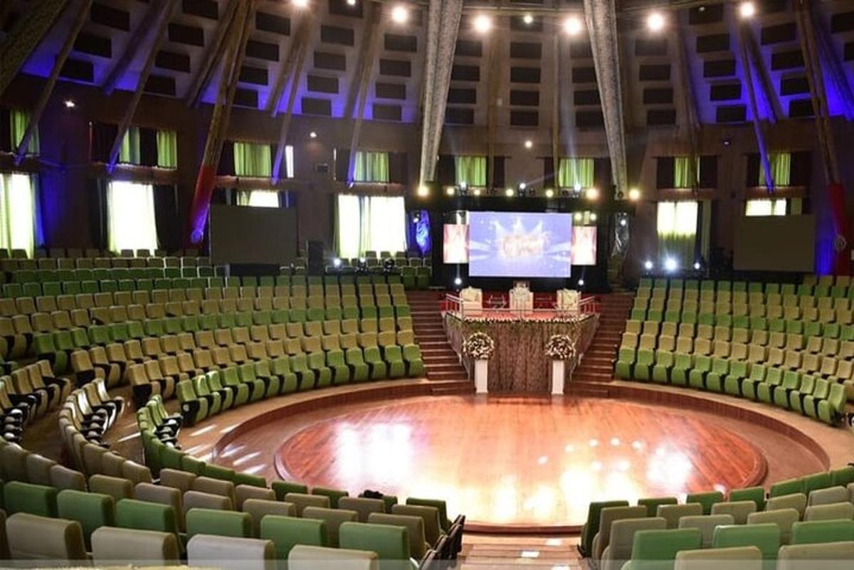 isang malaking auditorium na may mga berdeng upuan at isang entablado