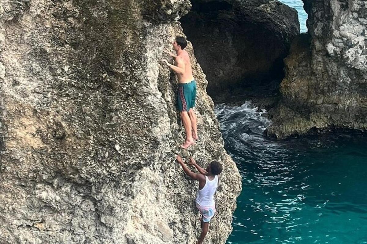 due uomini che si arrampicano su una roccia vicino all'acqua