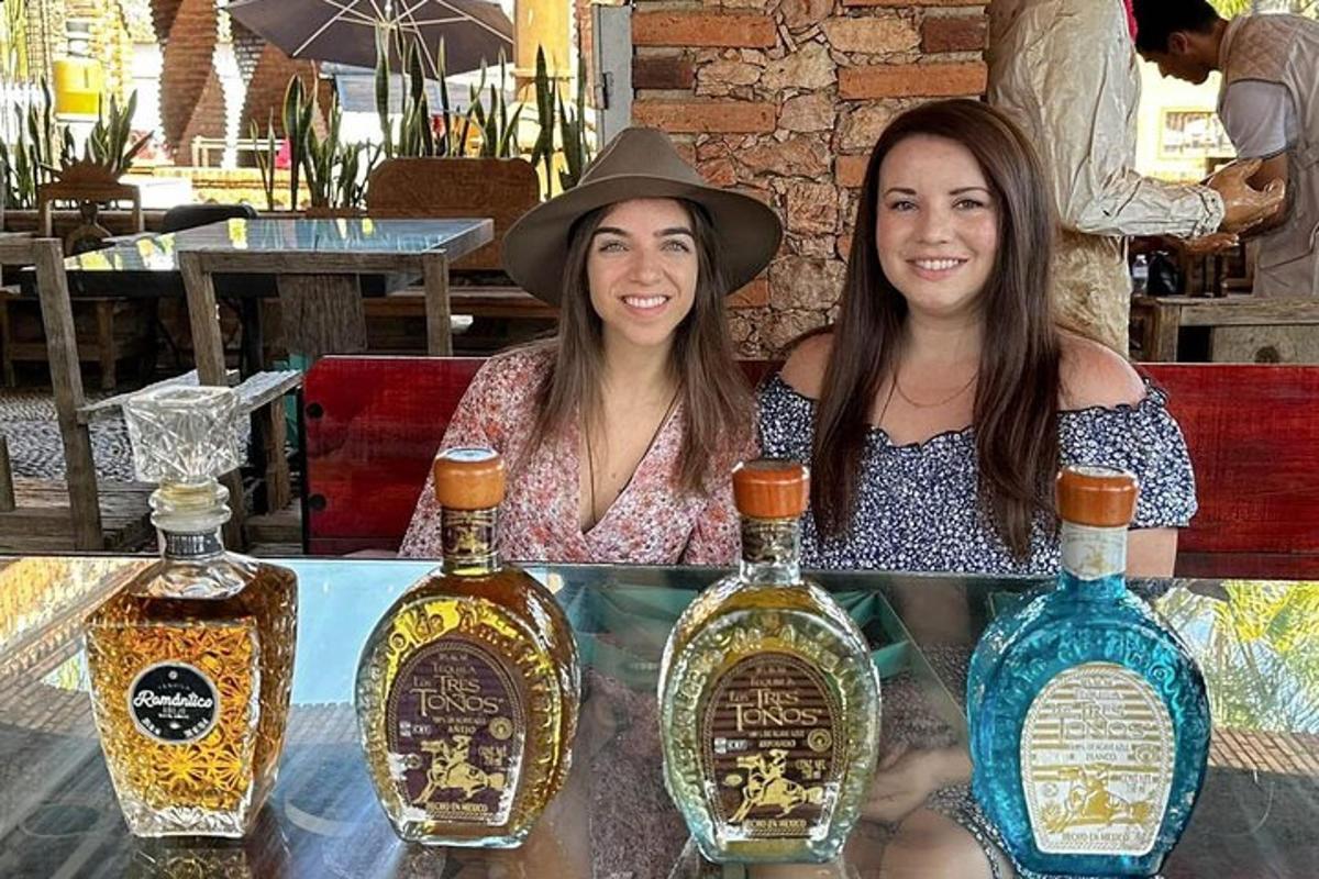 due donne sedute a un tavolo con bottiglie di alcolici