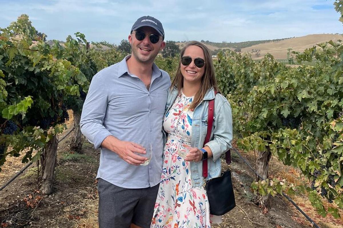 a man and a woman standing in a vineyard