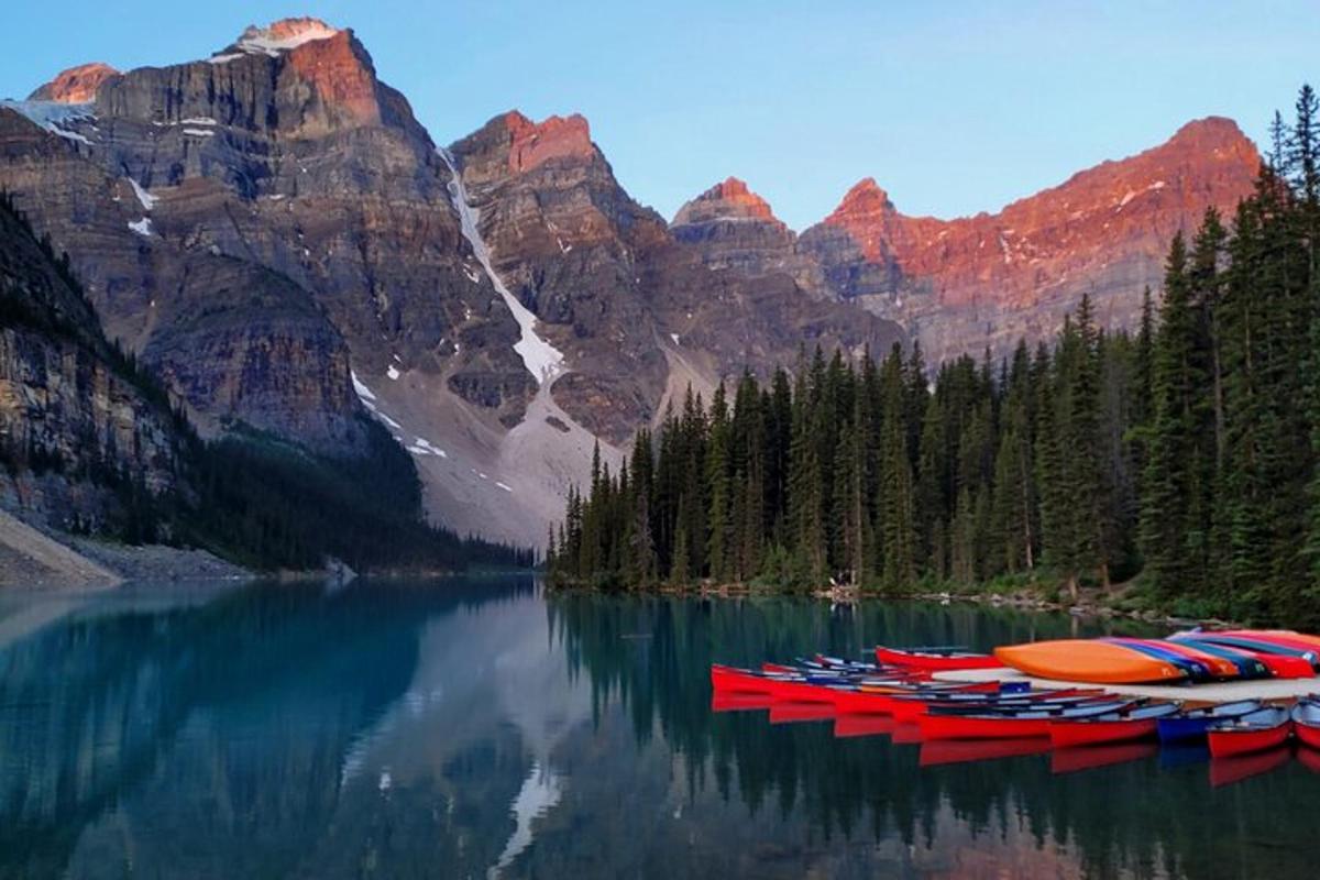 a group of red boats on a lake with mountains