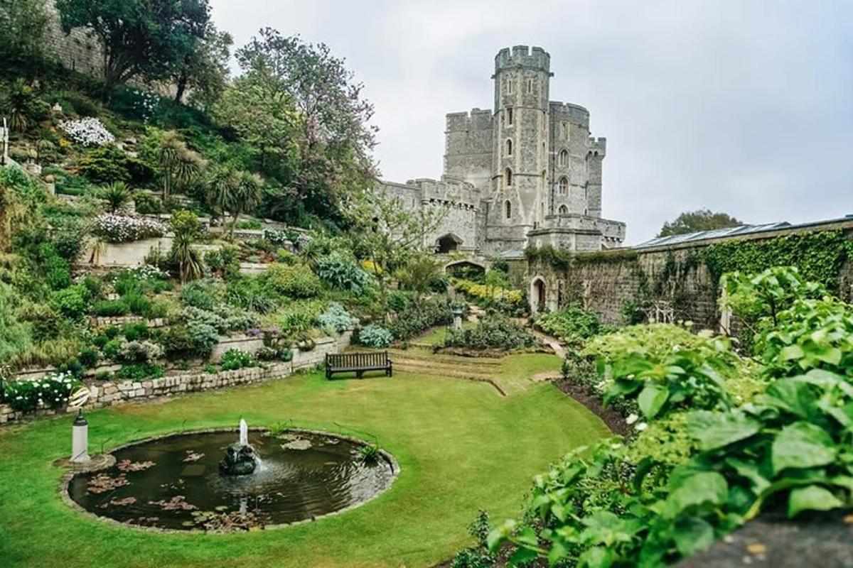 Un jardín con una fuente frente a un castillo.