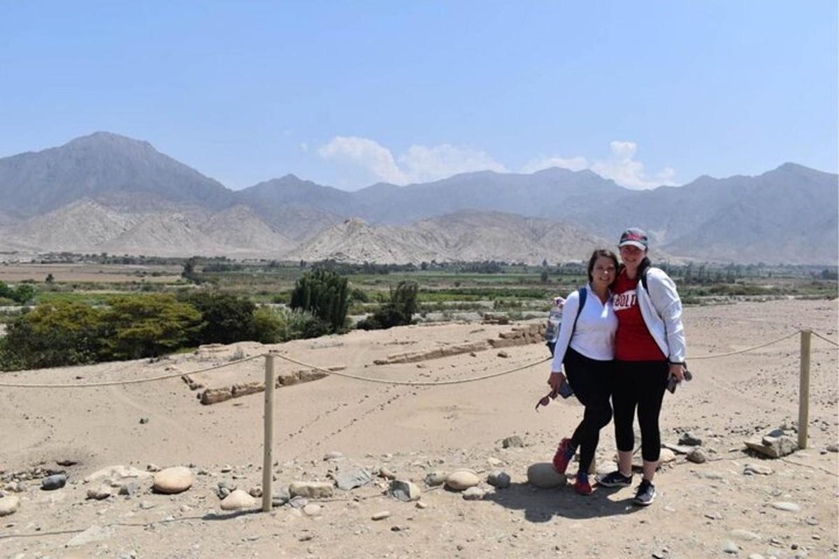 two people standing in the desert with mountains in the background