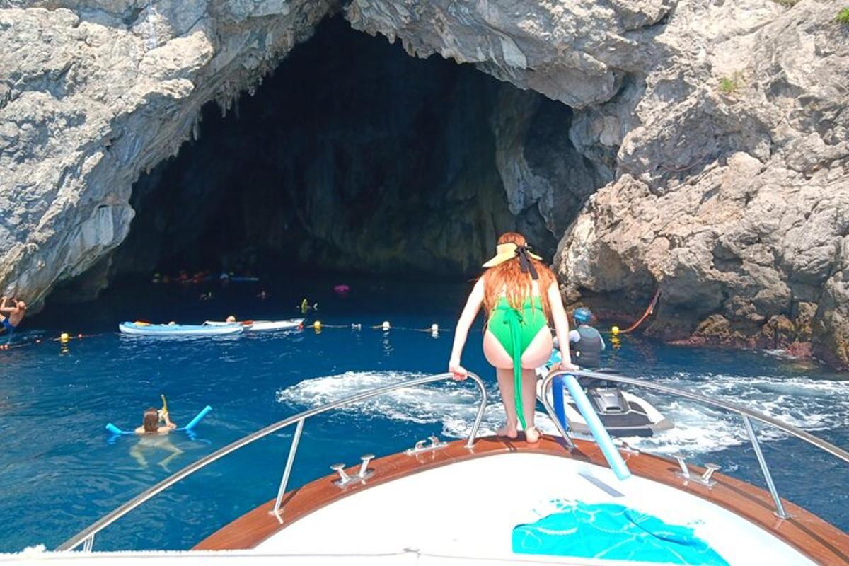 eine Frau in einem grünen Bikini steht auf einem Boot in einer Höhle