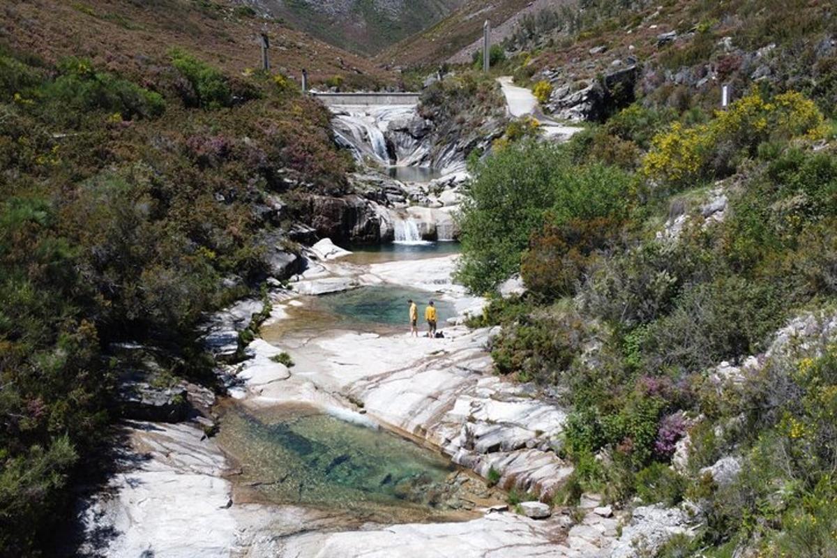 zwei Personen stehen in einem Fluss mit einem Wasserfall