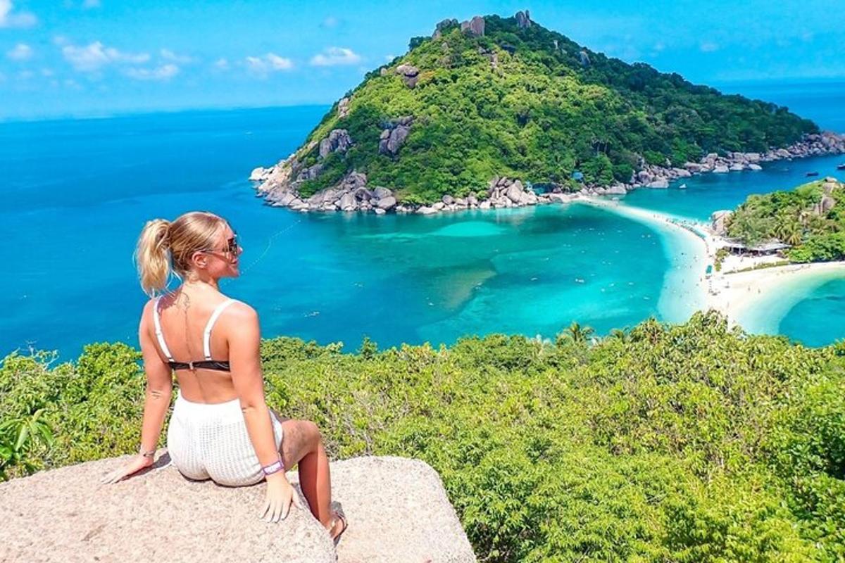 a woman sitting on a rock overlooking a beach